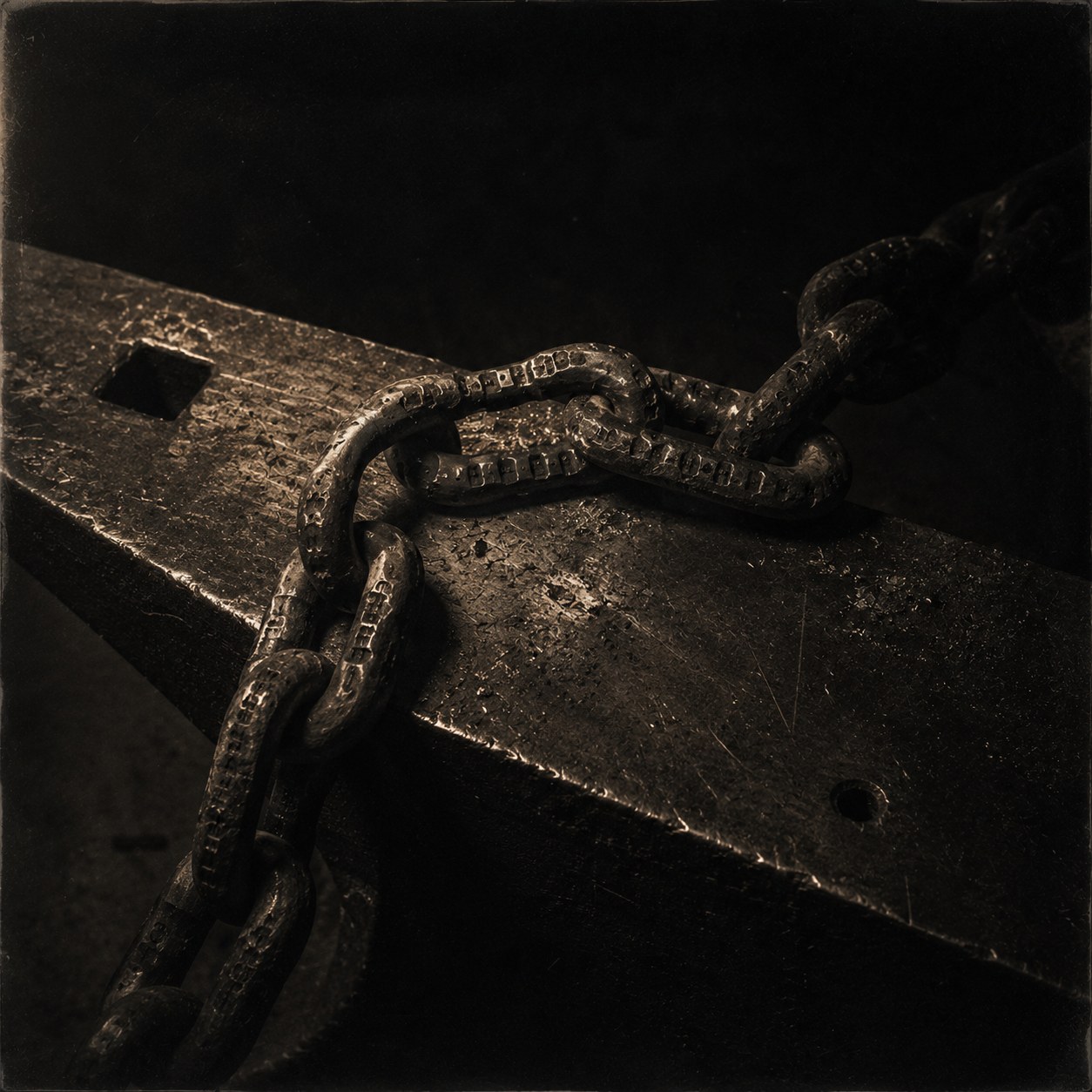 Plate I — a hand-forged chain across an anvil, every link carrying punched marks struck into the metal itself. The chain continues past the frame.